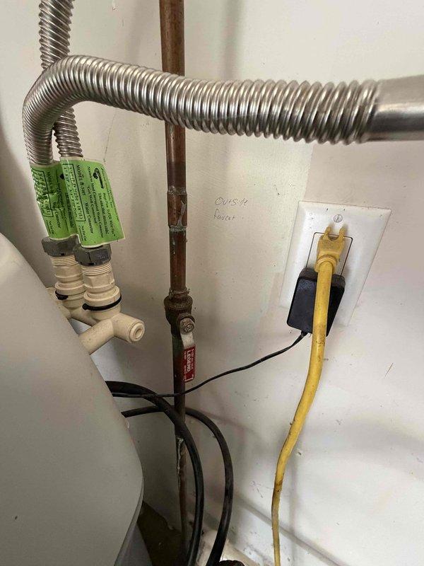 Completed professional installation of tankless water heater system in residential utility area. Installation included proper mounting of unit to wall, connection of copper supply lines, integration with existing water softener system, installation of pressure relief valve with appropriate safety components, electrical wiring with dedicated circuit and grounding, and flexible gas line connection using corrugated metallic tubing. All plumbing connections were secured with code-compliant fittings, electrical components were properly terminated and protected, and unit was tested for proper operation with digital display confirming system functionality.