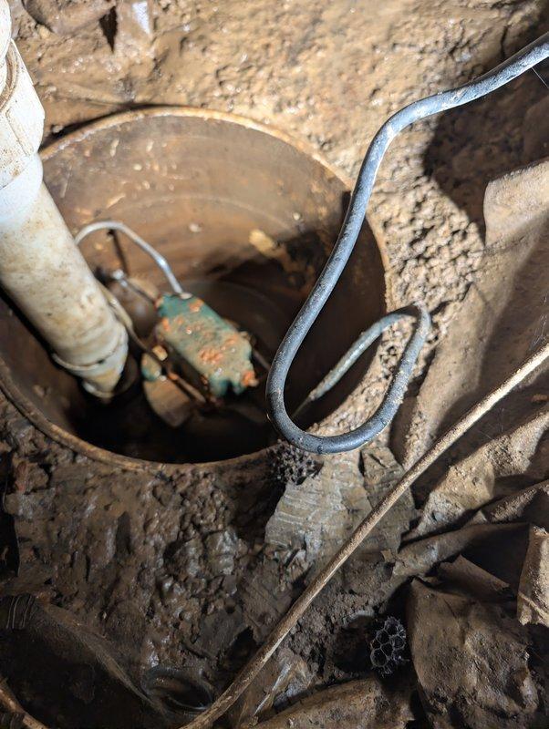 Responded to customer concern regarding inaudible sump pump operation. Performed on-site inspection of sump pump system, accessing crawl space to evaluate pump assembly, float mechanism, and associated components. Documented existing conditions showing significant corrosion on pump housing and mechanical components, with pump basin exhibiting heavy weathering and deterioration. Verified float operation and assessed overall system functionality to determine if pump was operating within normal parameters.