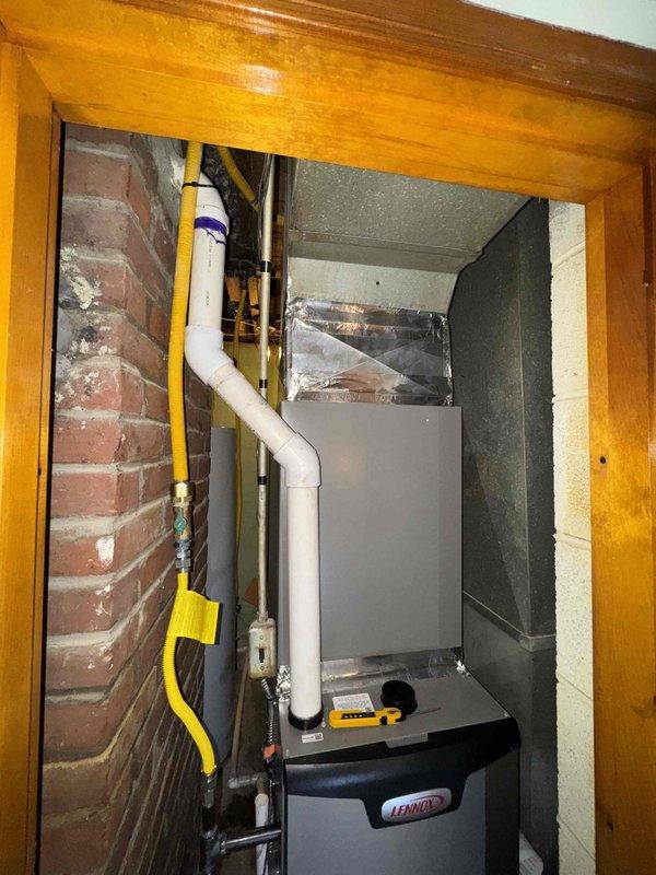 Completed full HVAC system installation in residential mechanical closet, including new Lennox furnace unit with associated gas line, venting, and ductwork connections. Installation included proper routing of yellow-jacketed gas supply line, white PVC condensate drainage and venting system, flexible aluminum ductwork, and electrical conduit within confined utility space featuring exposed brick wall construction. All components secured with appropriate mounting brackets and fittings, ensuring code-compliant integration with existing water heater and utility infrastructure in basement mechanical room.