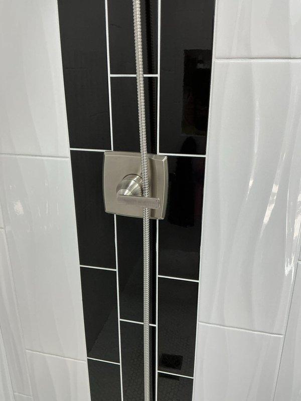 Responded to service call for leaking shower head in modern tiled shower installation. Upon inspection, evaluated Delta brand shower control panel with integrated handheld showerhead holder and flexible braided stainless steel hose. Diagnosed source of leak, performed necessary repairs to shower head assembly, and tested system for proper operation and water-tight seal. Confirmed no further leakage and restored shower to full functionality.
