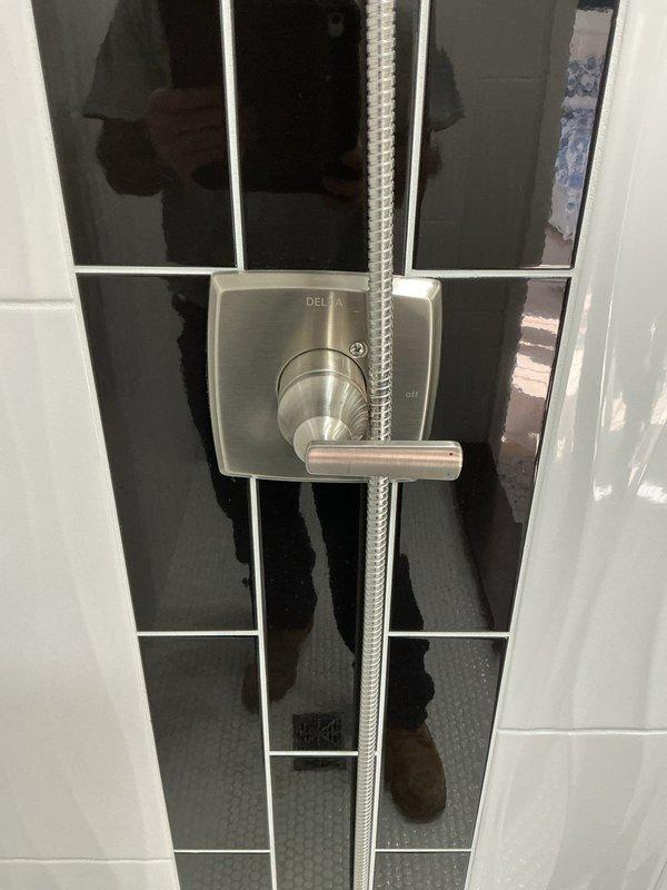Responded to service call for leaking shower head in modern tiled shower installation. Upon inspection, evaluated Delta brand shower control panel with integrated handheld showerhead holder and flexible braided stainless steel hose. Diagnosed source of leak, performed necessary repairs to shower head assembly, and tested system for proper operation and water-tight seal. Confirmed no further leakage and restored shower to full functionality.