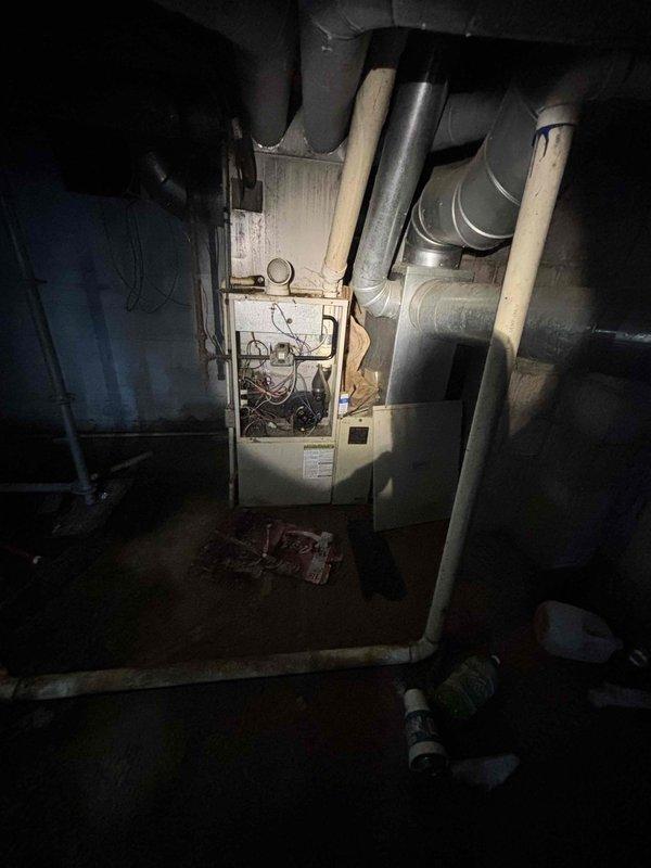 Responded to service call for failed HVAC system in 1872-built residential property with medium-sized heating and cooling requirements. Assessed 18-20 year old system with locked compressor in outdoor condensing unit. Inspected basement-installed natural gas/propane furnace and associated ductwork, noting age and condition of existing equipment. Documented existing HVAC infrastructure including furnace cabinet, duct connections, and exterior electrical disconnect. Provided comprehensive replacement estimate for complete system upgrade suitable for 1600-2200 square foot application with basement installation configuration.