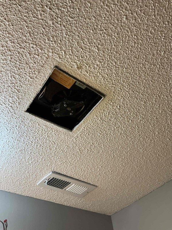 Responded to customer concern regarding debris discharge from bathroom exhaust fan following recent HVAC system installation. Customer reported insulation-like material expelling from bathroom vent when door closed, creating pressure differential. Conducted on-site inspection of bathroom exhaust fan and related ductwork. Examined ceiling-mounted ventilation components and documented conditions with photographs. Inspection revealed accessible mechanical components through ceiling opening, with floor register and exhaust fan assembly visible. Assessed air pressure dynamics between conditioned space and bathroom environment to identify source of material discharge and pressure imbalance issues related to new system operation.