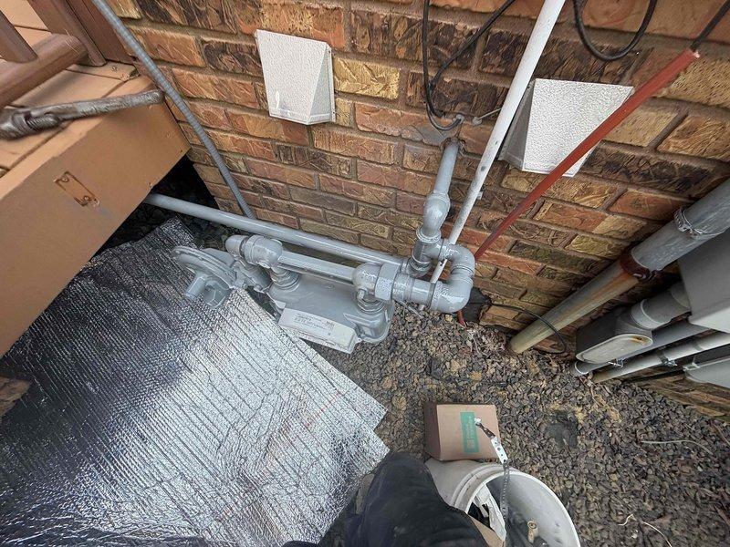 Completed follow-up electrical site visit to address gas pipe regulator installation. Installed regulator on gas line as previously coordinated, with required part having been staged for the appointment. Documented existing infrastructure in crawl space area, including gas piping configuration along structural brick wall and HVAC system location beneath exterior deck structure. Work completed and photographed for service records.
