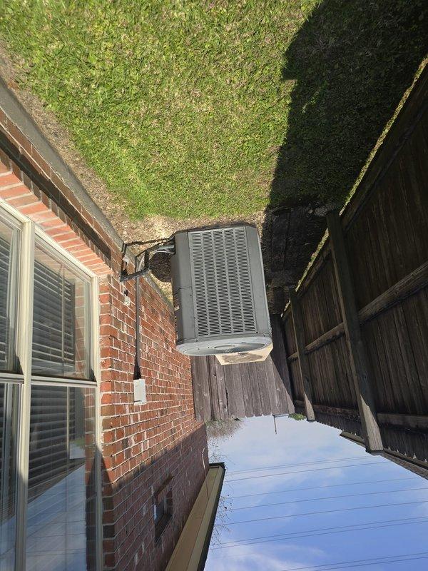 Conducted comprehensive assessment of 25-year-old residential HVAC system to determine replacement cost. Inspected exterior condensing unit located in side yard between brick wall and privacy fence, documenting equipment condition and installation configuration. Evaluated interior air handler unit and ductwork system in attic space, noting flexible metallic ductwork routing, insulation condition, and overall system accessibility for potential replacement considerations.