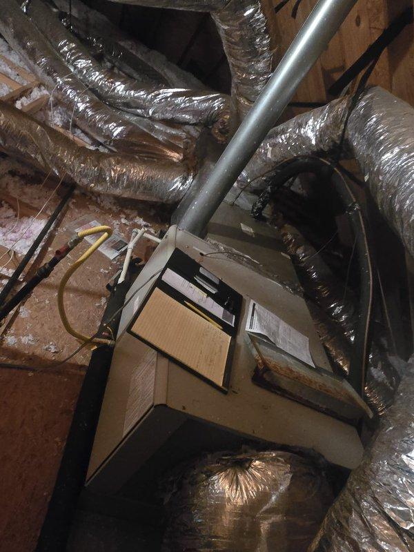 Completed comprehensive assessment of residential attic HVAC system installation. Documented existing air handling unit, flexible ductwork routing, and associated components including metallic piping, electrical conduit, and drainage lines positioned within confined crawl space between wooden joists and insulation.