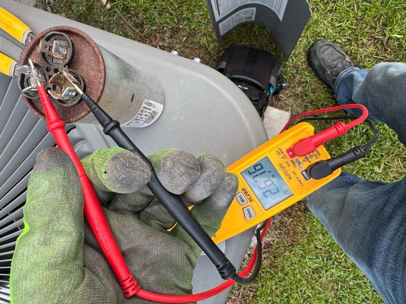 Responded to no cooling complaint on residential AC unit. Upon arrival, confirmed system was running but not producing cool air with thermostat functioning properly. Performed electrical diagnostics using digital multimeter at both the main electrical panel and outdoor condensing unit. Testing revealed failed capacitor at outdoor unit, evidenced by out-of-range readings and visible corrosion on terminal connections. Capacitor replacement required to restore proper compressor operation and cooling capacity.