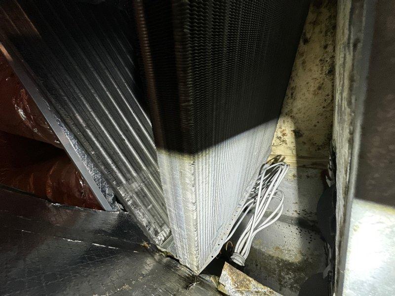 Completed annual cooling maintenance on residential HVAC system. Accessed evaporator coil assembly and air handler unit located in attic space. Inspected evaporator coil fins, noting dust accumulation on A-frame coil configuration. Examined copper refrigerant lines and electrical connections for proper operation. Replaced air filter at return air pleated media filter housing. Noted system appeared to be working harder than normal to maintain temperature setpoint, indicating potential airflow restriction or capacity issues. Verified filter replacement inventory available on-site for future maintenance visits. Documented equipment condition through photographic records showing coil assembly, drain pan with minor staining, and filter housing installation.