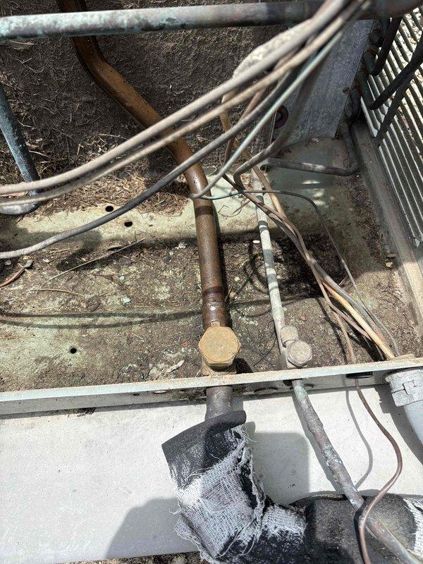 Performed diagnostic service on 26-year-old commercial HVAC unit serving climate-controlled storage building with reported no cooling and inoperative blower fan. Inspected outdoor condensing unit and verified previous diagnosis of failed condenser fan motor. Observed deteriorated refrigerant line insulation, weathered components, and significant aging throughout system. Documented equipment condition with photographs and provided repair quote as requested by owner who declined full system replacement.