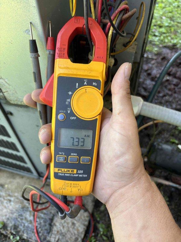 Completed spring maintenance on split system air conditioning unit at rental property. Performed comprehensive system inspection with indoor unit from 2019 and older outdoor unit. Utilized Fluke clamp meter to measure electrical current draw and voltage at outdoor condensing unit, verifying amperage readings and system electrical performance within manufacturer specifications at 233 volts. All electrical connections inspected and found secure with proper wire routing observed at disconnect box.