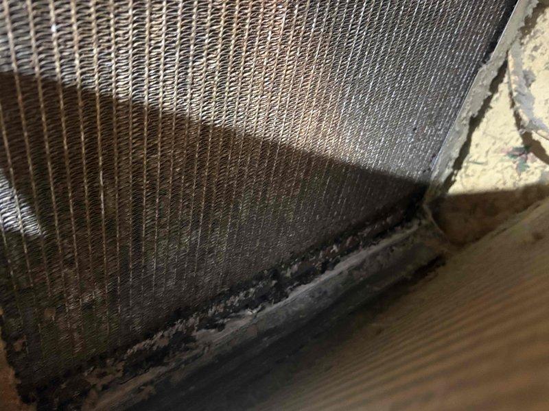 # AC Maintenance Service Completed

Performed comprehensive cleaning and inspection on single-system air conditioning unit as part of routine membership maintenance. Upon initial assessment, discovered significant contamination on evaporator coil assembly, including heavy accumulation of dirt, dust, and debris along the fin surfaces and base panels. Dark discoloration and caked buildup were evident in lower sections and crevices where fins meet the housing frame, indicating extended period without proper maintenance.

Conducted thorough coil cleaning to remove all contaminants and restore optimal heat transfer efficiency. Inspected condenser coil fins for damage and proper alignment. Documented pre-cleaning conditions showing contrast between contaminated and clean coil sections. All components returned to proper operating condition. System now operating at manufacturer specifications with improved airflow and heat exchange capability.