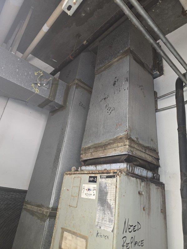 Conducted estimate for 1-ton HVAC system replacement. Documented existing Ameristar air handler unit with associated ductwork, refrigerant lines, and condensate drainage system. Noted deteriorated metal panel with visible rust and corrosion marked for replacement, along with aging ductwork requiring attention in kitchen area.