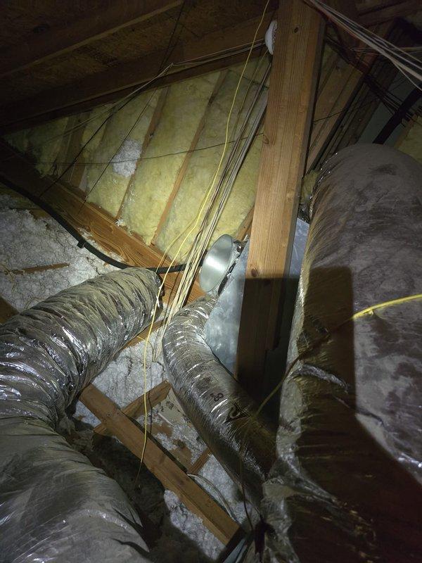 Performed second opinion evaluation on residential HVAC system with reported evaporator coil leak. Inspected attic-mounted air handler and associated ductwork, documenting system condition and configuration. Assessed flexible duct installation, insulation integrity, and overall system accessibility for potential evaporator coil replacement. Photographed existing equipment layout, ductwork routing through attic framing, and workspace constraints to support replacement estimate preparation.