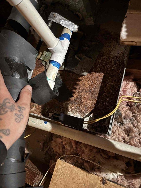 Performed maintenance inspection on 20-year-old electric air conditioning system. Upon examination, discovered severely corroded reversing valve and drain pan with extensive rust buildup and mineral deposits. Component showed significant deterioration with brownish-orange discoloration around valve ports and granular flaking on metal surfaces. Documented conditions with photographs showing compromised equipment integrity, white mineral efflorescence, and moisture damage throughout the attic installation. Advised customer of findings and recommended replacement of affected components due to advanced corrosion that could lead to system failure or refrigerant leaks.