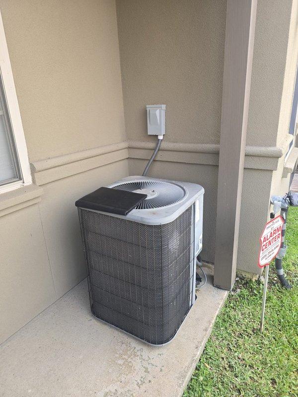 Completed installation of 3.5 ton Amana HVAC system including outdoor condensing unit positioned in protected alcove area with proper electrical disconnect and conduit routing. Unit installed on concrete pad with adequate clearance for airflow and serviceability, system commissioned and operational.