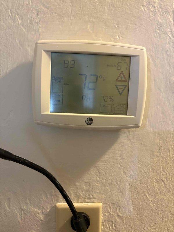 Responded to no cooling complaint with continuous fan operation. Upon arrival, found thermostat displaying 72°F setpoint with actual temperature reading of 89°F, indicating significant temperature differential and system failure to maintain desired cooling. Performed diagnostic inspection of HVAC system and identified severe water damage at air handler location with compromised insulation, deteriorated drywall, and moisture staining on surrounding surfaces. Documentation captured showing extensive structural damage affecting unit operation and performance. System requires immediate attention to address water intrusion source and damaged components preventing proper cooling cycle operation.