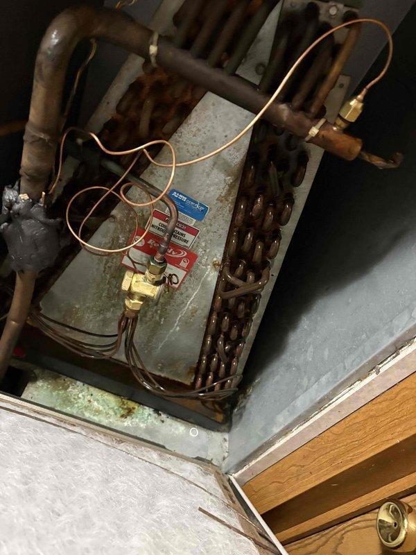 # Diagnostic Summary

Responded to customer complaint of air conditioning system running continuously without adequately cooling the space. Upon inspection, found HVAC system exhibiting significant age-related deterioration with heavy oxidation on copper refrigerant lines and extensive rust and corrosion throughout the evaporator coil assembly. Connected Fieldpiece digital manifold gauges to measure system pressures and temperatures. Readings indicated abnormal operating conditions with pressure at 244.4 PSIG and temperature reading of 793°F, suggesting potential refrigerant charge issues or compressor malfunction. The heavily corroded evaporator coil and deteriorated condition of refrigerant lines are likely contributing to reduced heat transfer efficiency and poor system performance. Service valves showed signs of age but remained accessible for testing. The extensive corrosion on internal components, combined with abnormal operating parameters, indicates system is operating well bey