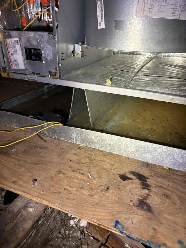 Responded to service call for non-functioning air conditioning system with suspected blower issue. Upon inspection of HVAC equipment in attic space, discovered significant standing water accumulation in drain pan beneath air handler unit, indicating clogged condensate drain line. Observed water damage and staining on surrounding plywood flooring from ongoing moisture exposure. Documented conditions of ductwork showing previous repairs and general wear. System evaluation revealed drainage failure as primary concern requiring immediate attention to prevent further water damage and restore proper AC operation.