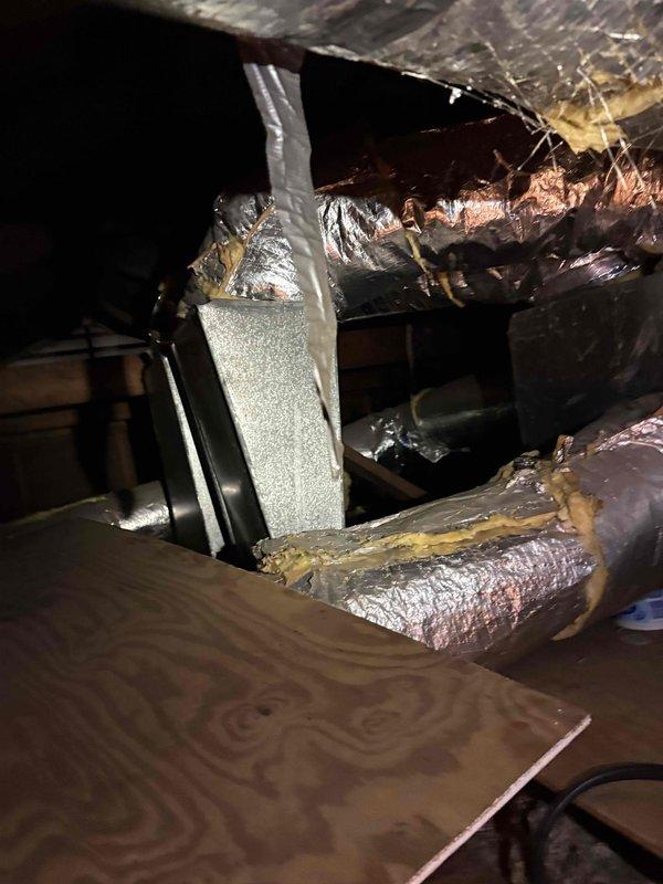 Responded to service call for non-functioning air conditioning system with suspected blower issue. Upon inspection of HVAC equipment in attic space, discovered significant standing water accumulation in drain pan beneath air handler unit, indicating clogged condensate drain line. Observed water damage and staining on surrounding plywood flooring from ongoing moisture exposure. Documented conditions of ductwork showing previous repairs and general wear. System evaluation revealed drainage failure as primary concern requiring immediate attention to prevent further water damage and restore proper AC operation.