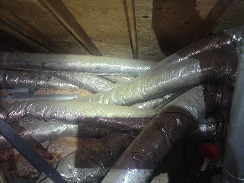 Conducted attic inspection and provided estimate for ductwork replacement and repair. Documented existing HVAC duct system showing aged flexible ductwork with visible wear, discoloration, and compromised insulation wrapping throughout the attic space, requiring replacement to restore proper system efficiency and air distribution.