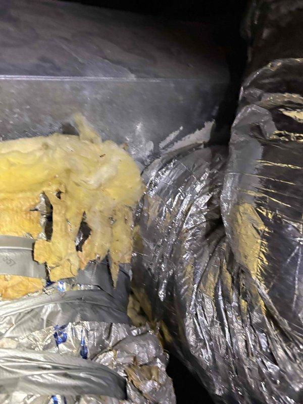 Responded to diagnostic call for property with three 5-ton HVAC systems experiencing recurring fuse failures and complete loss of airflow to spa room. Inspected problematic unit in attic space and documented conditions of ductwork, insulation, and system components. Found disturbed and deteriorated fiberglass insulation around flexible aluminum ductwork with visible gaps at connection points. Assessed blower motor operation, electrical connections, and duct integrity to determine root cause of airflow restriction and electrical issues requiring further corrective action.
