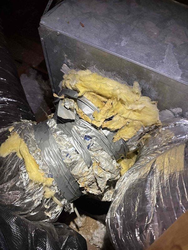 Responded to diagnostic call for property with three 5-ton HVAC systems experiencing recurring fuse failures and complete loss of airflow to spa room. Inspected problematic unit in attic space and documented conditions of ductwork, insulation, and system components. Found disturbed and deteriorated fiberglass insulation around flexible aluminum ductwork with visible gaps at connection points. Assessed blower motor operation, electrical connections, and duct integrity to determine root cause of airflow restriction and electrical issues requiring further corrective action.