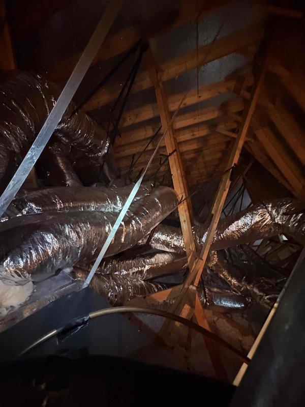 Performed quality assurance inspection on recently installed Amana HVAC system due to concerns about excessive runtime and increased utility consumption. Upon inspection, discovered significant damage to attic ductwork including torn metallic vapor barrier wrapping with exposed fiberglass insulation, and improperly installed flexible ductwork that was compressed and inadequately supported throughout the attic space. These deficiencies were causing substantial air leakage and reduced system efficiency, resulting in extended equipment runtime to maintain temperature setpoints. Documented all findings with photographs and obtained required manufacturer paperwork signatures from homeowner.