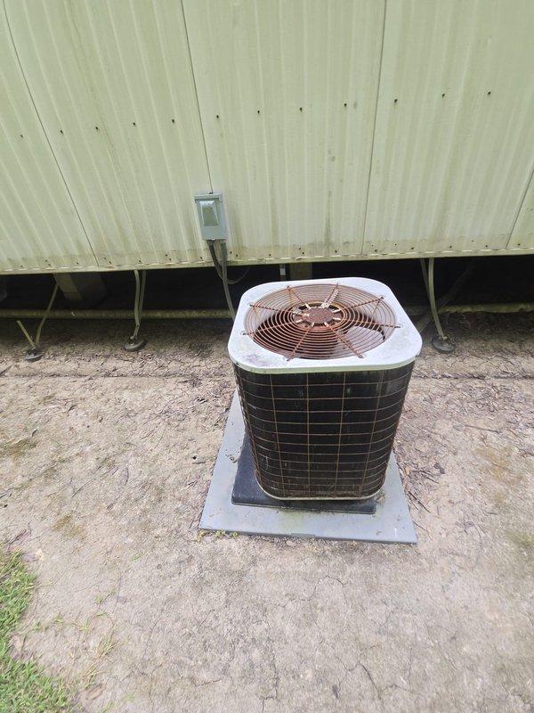 Completed estimate for residential air conditioning condenser replacement. Inspected existing outdoor condenser unit with white top cover and dark metal grille housing positioned on concrete pad against building exterior, noting electrical conduit connection from wall-mounted panel. Assessed interior HVAC closet location with louvered ventilation door to verify system configuration and access requirements for replacement installation.