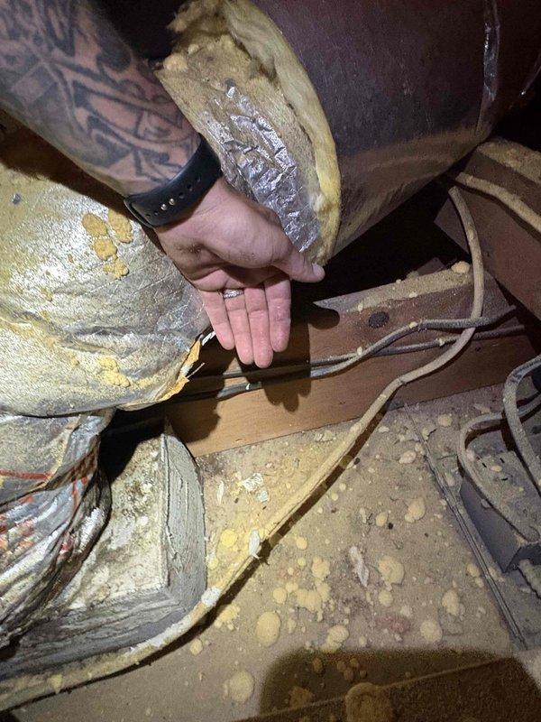 Responded to customer report of water leak originating from upper level and affecting lower areas. Accessed attic space to conduct thorough diagnostic inspection of potential moisture intrusion sources. Examined exposed structural framing, HVAC ductwork, and insulation materials for signs of active leaking, water staining, or condensation issues. Inspected silver-wrapped duct systems and connection points where foam insulation and metallic tape joins were present, checking for compromised seals that could allow condensation to form and drip. Evaluated wooden joists and framing members for water damage, discoloration, or deterioration. Assessed condition of fiberglass insulation for saturation or compression indicating moisture exposure. Documented findings with photographic evidence showing attic infrastructure, ductwork configuration, and structural components to support further evaluation and repair recommendations.