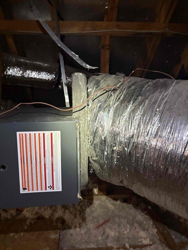 Responded to after hours service call for air conditioning system experiencing repeated freeze-up conditions. Upon arrival, unit was powered off with only the air handler fan operating. Performed diagnostic inspection of HVAC system installed in attic space. Examined air handler unit, flexible ductwork installation, and associated components. Documented system configuration including metallic flexible ducts properly secured with metal straps to wooden framing, insulated air handler panels, and copper refrigerant lines. Assessed overall condition of ductwork insulation and verified proper installation methods. System appeared to be approximately ten years old based on visual inspection. Captured photographic documentation of attic-mounted equipment, duct routing, and installation details for service records.