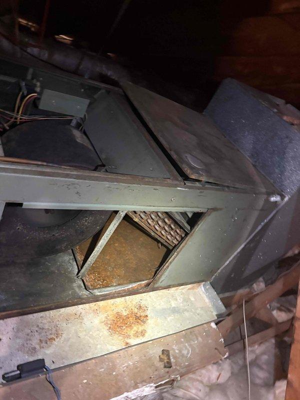 Responded to no-cooling call with reported frozen refrigerant line on aging attic-mounted air handler unit. Upon inspection, found extremely dirty blower wheel with heavy dust and debris accumulation restricting airflow, along with heavily soiled evaporator coil visible through access panel. Unit exhibited significant age-related wear with rust staining on interior metal surfaces and dusty internal components throughout cabinet. Documented existing conditions with photos showing compromised blower assembly, deteriorated coil section, and overall poor maintenance history. System requires thorough cleaning of blower wheel and evaporator coil to restore proper airflow and prevent future freeze-ups, along with comprehensive evaluation of refrigerant charge once airflow is corrected.