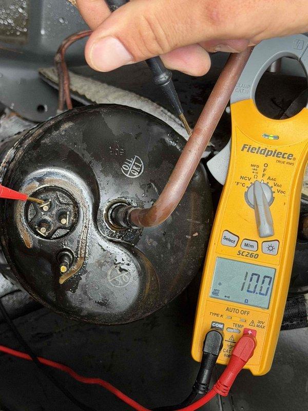 Responded to no cooling complaint on downstairs HVAC system in home with two approximately 20-year-old units. Upon arrival, performed electrical diagnostics on the downstairs outdoor unit compressor. Using digital multimeter, tested compressor motor windings and electrical connections to determine operational status. Measurements indicated compressor failure, preventing the downstairs system from operating. Upstairs system confirmed to be running continuously in attempt to compensate for non-functional downstairs unit, causing inadequate cooling throughout home. Documented findings with diagnostic photos showing compressor testing procedures and meter readings. Advised that downstairs system requires compressor replacement or full outdoor unit replacement due to age of equipment. Recommended evaluation of both systems given their advanced age and potential for additional component failures.