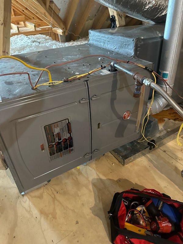 Completed no-charge member maintenance inspection and cleaning on 3-year-old 5-ton Rheem gas system. Performed comprehensive system evaluation including air handler inspection in attic space, verified proper operation of all components, checked refrigerant lines and connections, and cleaned unit as needed. Documented equipment condition with photos showing air handler unit, ductwork configuration, and overall system installation in attic environment.