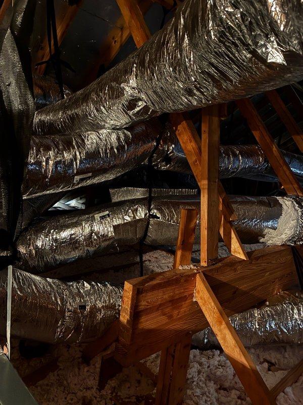 # Large HVAC Installation - Attic Ductwork Assessment and Correction Plan

Conducted comprehensive evaluation of newly installed HVAC ductwork system in residential attic space. Inspection revealed multiple deficiencies requiring immediate attention to ensure proper system performance and efficiency.

## Primary Issues Identified

**Airflow Restrictions:** Discovered flexible ductwork installed with excessive kinking and compression throughout attic space. Multiple duct runs improperly routed, creating sharp bends and restrictions that significantly impede airflow and reduce system capacity. Documented improper installation techniques affecting overall HVAC performance.

**Return Air Leakage:** Identified unsealed return air collars at multiple connection points. Gaps at collar interfaces allowing hot attic air infiltration into return air stream, compromising system efficiency and indoor air quality. This condition forces system to condition unconditioned attic air, increasing energy 
