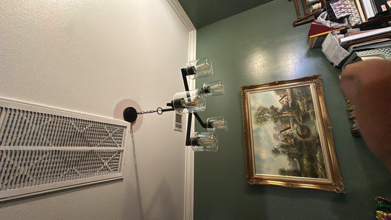 Installed two modern chandelier-style light fixtures in residential living space, each featuring four clear glass bulb holders with black metal arms mounted to ceiling via circular mounting plates and chain suspension. Verified proper electrical connections, tested fixture operation, and ensured secure mounting in accordance with manufacturer specifications and electrical code requirements.