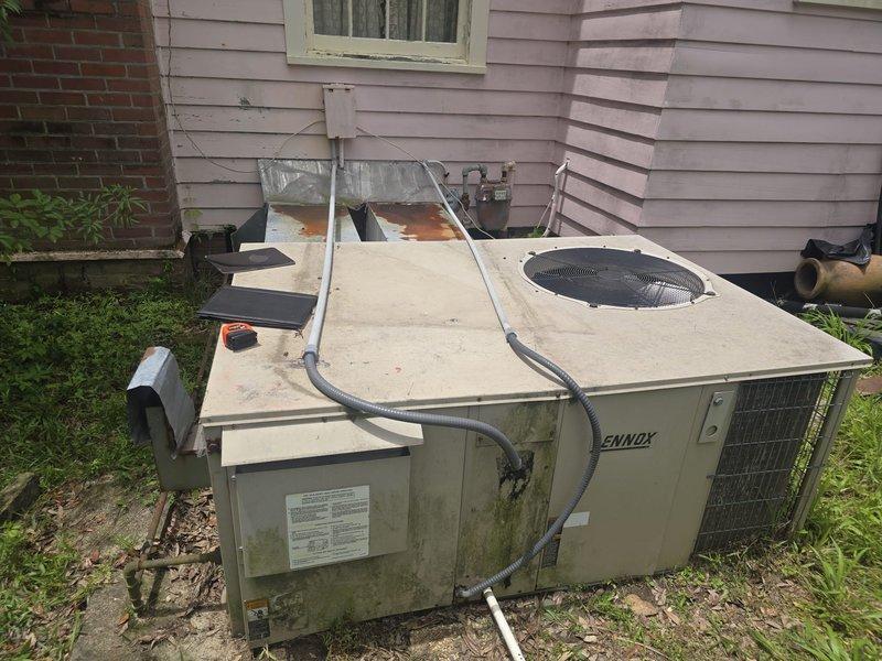Conducted on-site estimate for downstairs HVAC system replacement. Evaluated existing 1996 Trane package unit showing significant age-related deterioration, including weathered exterior panels, discoloration, algae growth, and visible wear on cabinet surfaces. Documented current equipment condition through photography, noting exposed internal components and copper coil assembly, and provided replacement recommendations for the aging packaged air conditioning system.