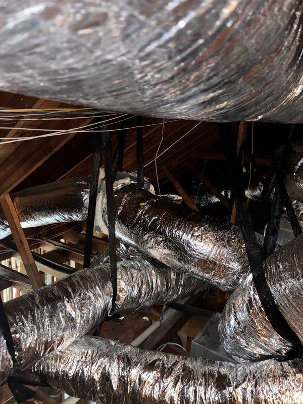 # Install - Small: HVAC System Completion

Completed final installation work on residential HVAC system in preparation for inspection. The scope included a complete air handler unit installation in the attic space with associated ductwork routing and connections.

## Work Performed

Installed central air handler unit on elevated platform in attic space with proper support and clearances for service access. Routed and secured multiple runs of insulated flexible ductwork throughout the attic, connecting supply and return air pathways to the air handler. Ductwork was properly supported on wooden structural members and secured to prevent sagging or disconnection.

Verified all duct connections were sealed and insulated flexible ducting was routed to minimize compression and maintain efficient airflow. Ensured adequate working clearances around equipment per manufacturer specifications and local code requirements.

Conducted final walkthrough and documentation of installation with photograp