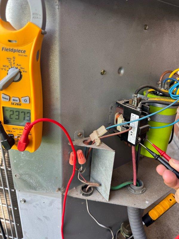 Responded to service call for 2012 Carrier system experiencing difficulty maintaining desired temperature during daytime operation. Customer reported capacitor replacement approximately three months prior. Upon arrival, performed diagnostic testing of electrical components using digital multimeter, which revealed voltage reading of 23.73V at control board. Inspected contactor, relay assembly, and capacitor connections within control cabinet. All wire terminations, including power and control wiring, were examined for proper connections and signs of failure. System evaluation completed and findings documented with photographic evidence of electrical components and exterior unit location.