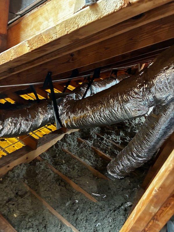 Completed full ductwork replacement in residential attic space, removing all existing 10" flex ducts and installing new 9x7x7 rectangular flex duct runs throughout the system. Replaced supply plenum with new unit and modified bedroom supply box to 12x6x8 configuration with dedicated 8" duct run to bedroom for improved airflow. Retained existing 6" and 8" round ducts where appropriate and installed two additional 7" collars on plenum to accommodate alternate duct configurations. All flex ductwork properly secured with straps to ceiling joists and routed to minimize compression and sagging for optimal HVAC system performance.