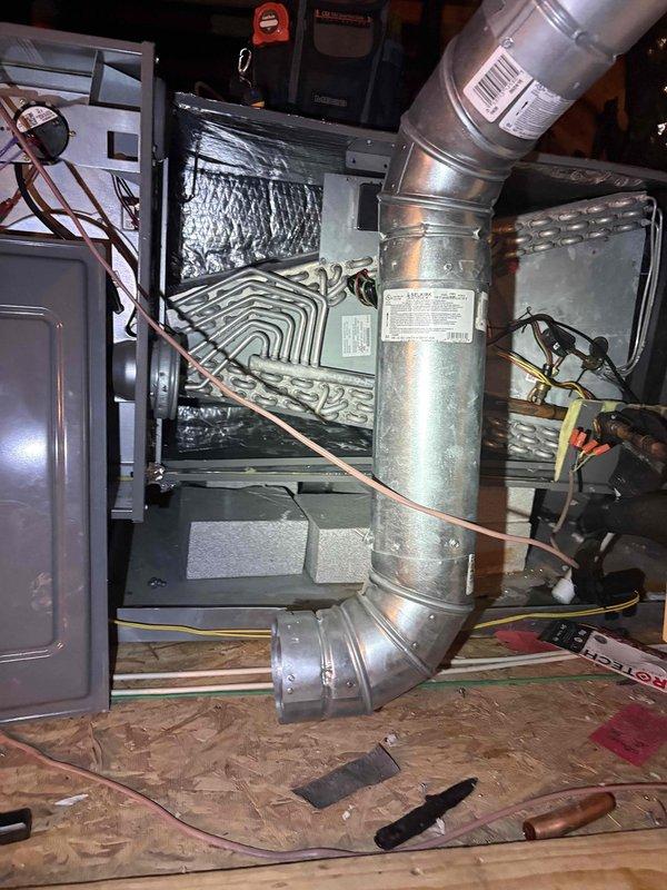 Responded to callback for HVAC system displaying thermostat error message and shutting down unit. Upon arrival, confirmed customer had bypassed thermostat to restore temporary cooling operation. Inspected air handler unit in attic space and verified system components including ductwork connections, refrigerant lines, and electrical wiring. Performed electrical diagnostics using clamp meter to measure amperage draw, which registered 0.00A on primary reading with secondary measurement of 8.44, indicating potential issues with system power or control circuit. Documented equipment condition and installation configuration with photographs for further analysis and repair planning.
