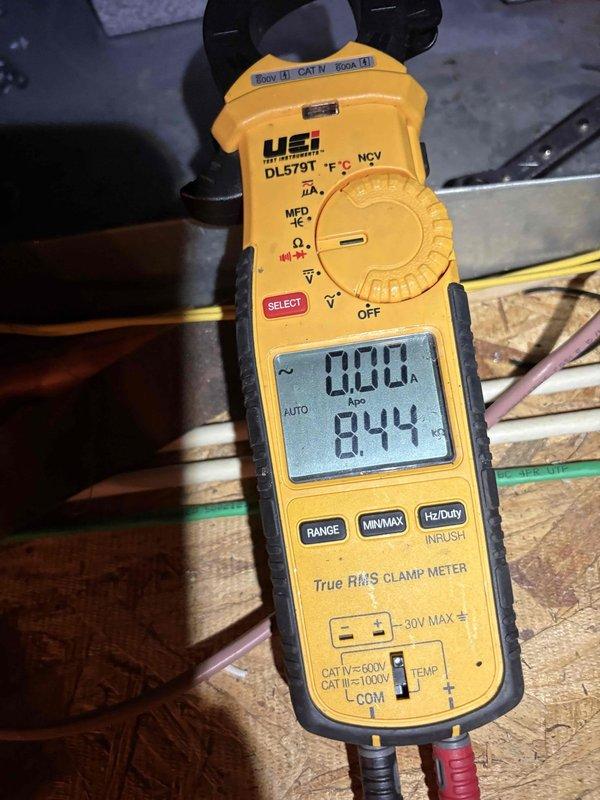 Responded to callback for HVAC system displaying thermostat error message and shutting down unit. Upon arrival, confirmed customer had bypassed thermostat to restore temporary cooling operation. Inspected air handler unit in attic space and verified system components including ductwork connections, refrigerant lines, and electrical wiring. Performed electrical diagnostics using clamp meter to measure amperage draw, which registered 0.00A on primary reading with secondary measurement of 8.44, indicating potential issues with system power or control circuit. Documented equipment condition and installation configuration with photographs for further analysis and repair planning.