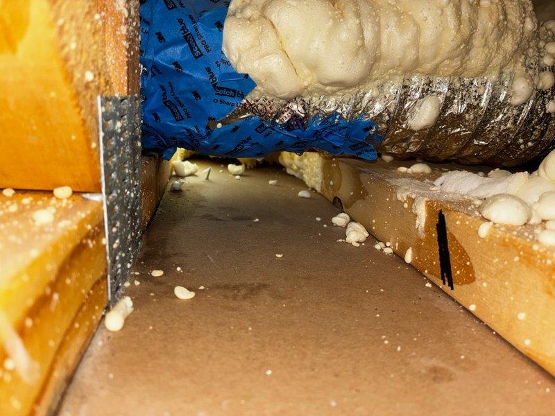 Responded to report of water leak in master bedroom ceiling suspected to be from AC condensate line. Accessed attic space through existing ceiling opening and inspected area above affected room. Located flexible ductwork and insulation in crawl space with evidence of moisture intrusion and debris accumulation on attic floor. Documented conditions with photos showing blue flexible duct, compressed insulation, and structural elements with expanding foam insulation applications. Identified potential condensate drainage issue requiring further evaluation and repair of AC system drainage components.