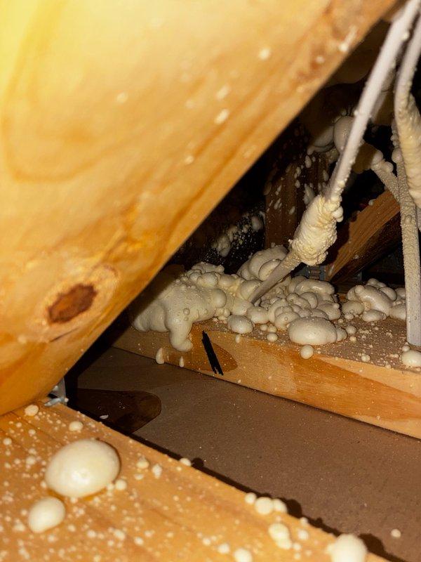 Responded to report of water leak in master bedroom ceiling suspected to be from AC condensate line. Accessed attic space through existing ceiling opening and inspected area above affected room. Located flexible ductwork and insulation in crawl space with evidence of moisture intrusion and debris accumulation on attic floor. Documented conditions with photos showing blue flexible duct, compressed insulation, and structural elements with expanding foam insulation applications. Identified potential condensate drainage issue requiring further evaluation and repair of AC system drainage components.
