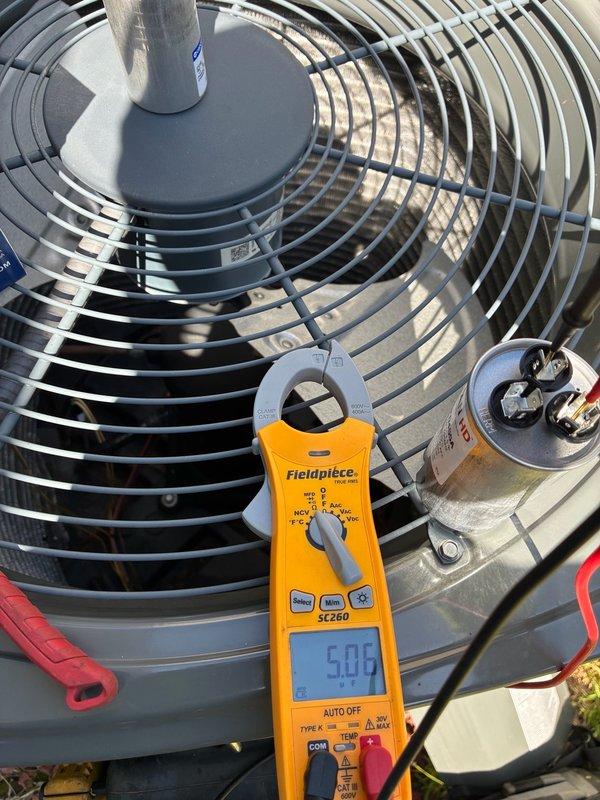 # HVAC Condenser Fan Motor Failure

Responded to no cooling complaint with indoor temperature at 82°F. Thermostat calling for cooling but outdoor unit fan not operating. Performed diagnostic testing on single-zone electric air conditioning system. Used clamp meter to verify amperage draw on condenser fan motor, which measured 5.08 amps. Inspected fan motor assembly, capacitor, and associated electrical connections. Fan motor determined to be inoperative despite proper capacitor and electrical supply. Photographed diagnostic readings and capacitor wiring configuration showing multiple wire connections with terminal blocks. Capacitor appeared serviceable with proper connections intact. Issue isolated to failed condenser fan motor preventing heat rejection from outdoor unit.
