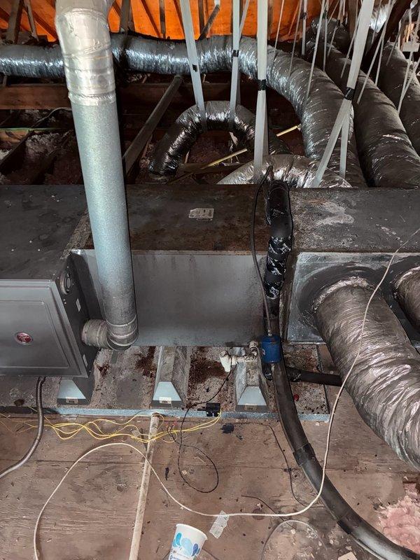 Responded to no cooling complaint on residential HVAC system in late 1980s/early 1990s home. Upon arrival, customer reported system running but not producing cold air with no visible ice formation on refrigerant lines. Accessed attic-mounted air handler and inspected HVAC equipment, ductwork, and refrigerant lines. Documented existing conditions including flexible duct routing, air handler installation, and attic space configuration. System evaluation performed to diagnose cooling deficiency and determine necessary repairs.
