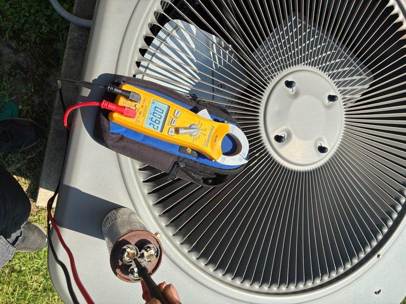 Responded to no-cooling complaint on residential air conditioning system. Upon arrival, performed electrical diagnostics on outdoor condenser unit using clamp meter to measure voltage and amperage at capacitor terminals. Testing revealed capacitor failure with readings of 360V and 45.0µF, outside acceptable operating parameters. Replaced defective run capacitor, verified proper electrical connections, and confirmed system returned to normal cooling operation with appropriate voltage and amperage readings.