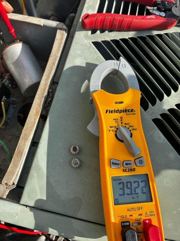 Installed replacement capacitor on HVAC unit. Verified system operation with clamp meter reading of 392, confirming proper amperage draw and successful component installation.