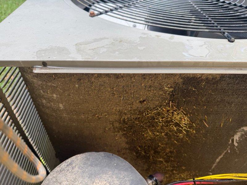 # After Hours Emergency Dispatch

Responded to emergency call regarding full overflow drain pan. Upon arrival, advised customer to shut down system immediately to prevent water damage. Inspection revealed severe frost buildup on refrigerant lines indicating restricted airflow or low refrigerant charge. Documented heavy accumulation of dirt, debris, and organic material on outdoor condenser unit components, which was likely contributing to system malfunction. Observed water staining on wooden platform and surrounding areas consistent with ongoing condensation issues. Unit age estimated at 15+ years based on installation timeframe provided. Photographed frozen evaporator components and contaminated condenser coil for documentation purposes. Recommended immediate follow-up service appointment for thorough system cleaning, refrigerant charge verification, and drain line clearing to restore proper operation and prevent further water overflow.