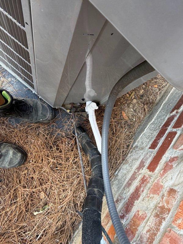 Responded to callback for outdoor HVAC unit experiencing freezing issues following recent compressor replacement. Inspected Carrier system (Model 58CVA070, Serial 1217A15474, manufactured March 2017) and refrigerant line configuration running from outdoor unit to indoor components. Documented current installation condition including refrigerant lines with insulation and overall system setup to assess potential causes of freeze-up condition such as refrigerant charge levels, airflow restrictions, or metering device issues related to recent compressor service.