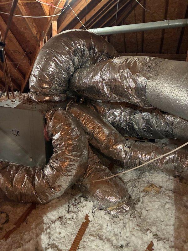 Performed no-charge second opinion inspection of attic ductwork after another contractor identified a disconnected trunk line. Confirmed 10-inch flexible trunk line detached from 12x6 supply drop, actively discharging conditioned air into attic space instead of living area. Documented existing conditions with photographs showing loose ductwork coiled in attic with blown insulation and standard HVAC infrastructure. Assessed scope of repair required to properly reattach and secure disconnected duct section to restore proper airflow to intended zone.